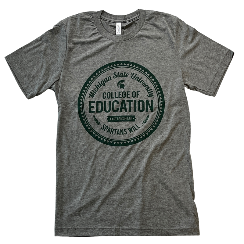 Medium heather gray short-sleeve crewneck t-shirt. In the center is a circular graphic reading Michigan State University College of Educations: Spartans Will in a variety of fonts with retro icons and the Spartan helmet. The graphic is printed in forest green.