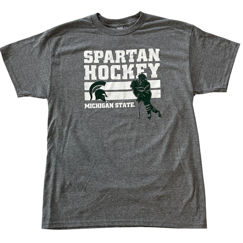 A gray tee shirt with "Spartan Hockey" written in all caps. Underneath the writing is a green silhouette of a hockey player and a MSU spartan helmet logo, with "Michigan State" written underneath.