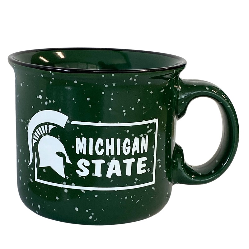 A dark green campfire style mug with a curved handle made of heavy duty ceramic. The exterior has a soft white speckle pattern and a logo featuring a white Spartan helmet and the words "Michigan State" within a white rectangle border.