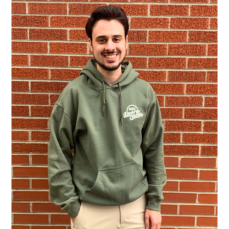 Man standing in front of a brick wall with a green hoodie with a kangaroo pocker and a white MSU Dairy Store logo on left chest.