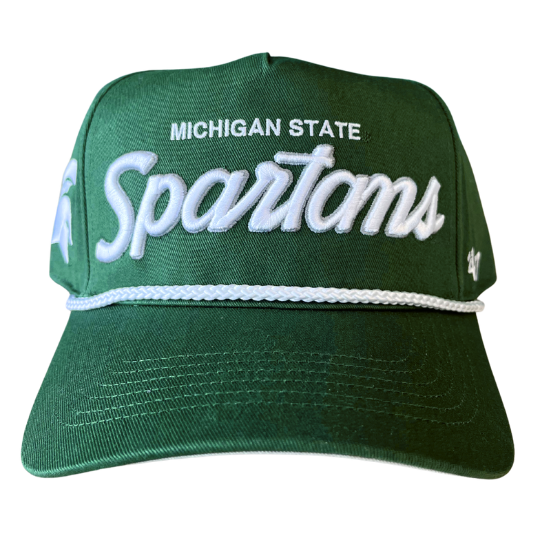 A head-on view of a green baseball cap with Michigan State embroidered in white above an embroidered stylized script reading “Spartans” in white with a silver outline. Embroidered on the right temple panel is a white Spartan helmet, and the left temple panel features an embroidered ’47 logo in white. Over the bill is a white braided cord.