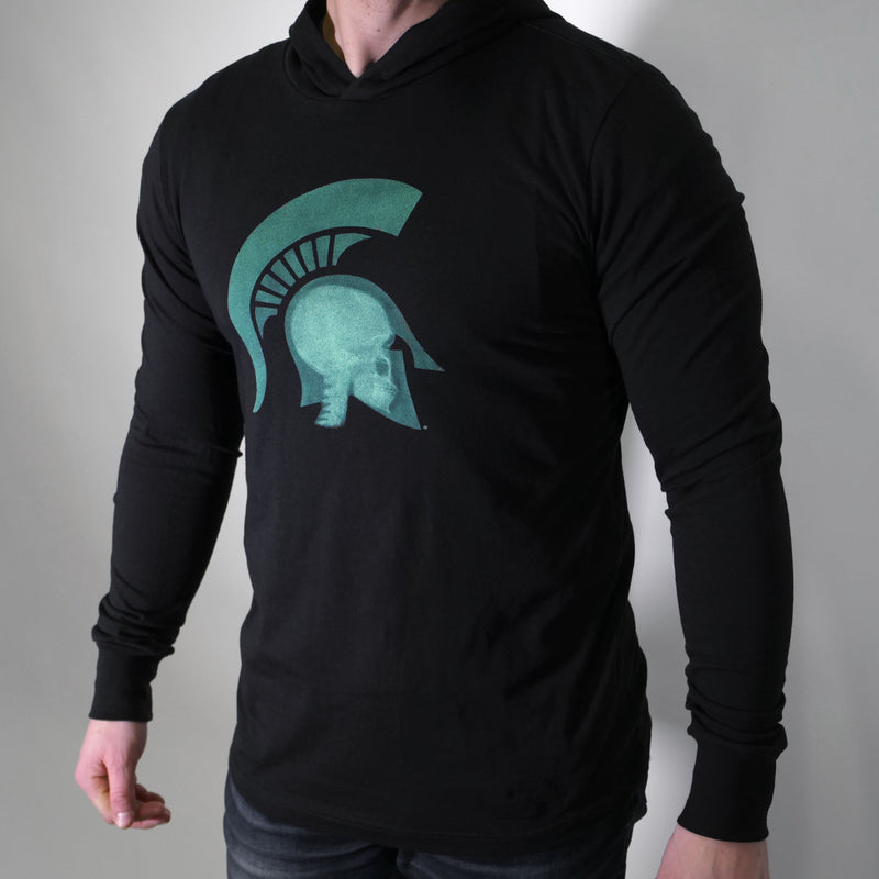 Front view of a man wearing a black long-sleeve crewneck t-shirt with a hood built-in. On the center chest is a graphic of an x-ray of a head wearing a Spartan helmet