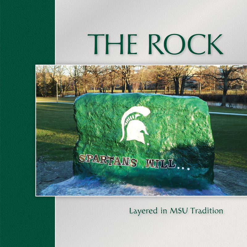 Cover of the "The Rock: Layered in MSU Tradition" Coffee Table Book featuring a picture of the rock painted with the text Spartans Will
