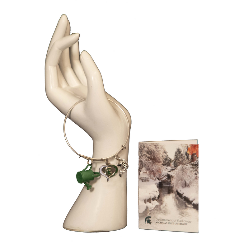 The silver water and koi bracelet on a hand mannequin next to a greeting card featuring a photo of the red cedar river in winter.