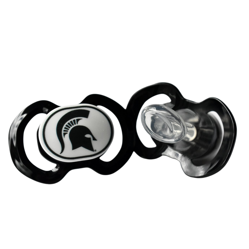 Two black pacified side by side. On the left, the front of one pacifier with a white center piece displaying a black Spartan helmet. The other pacified shows the mouth piece.