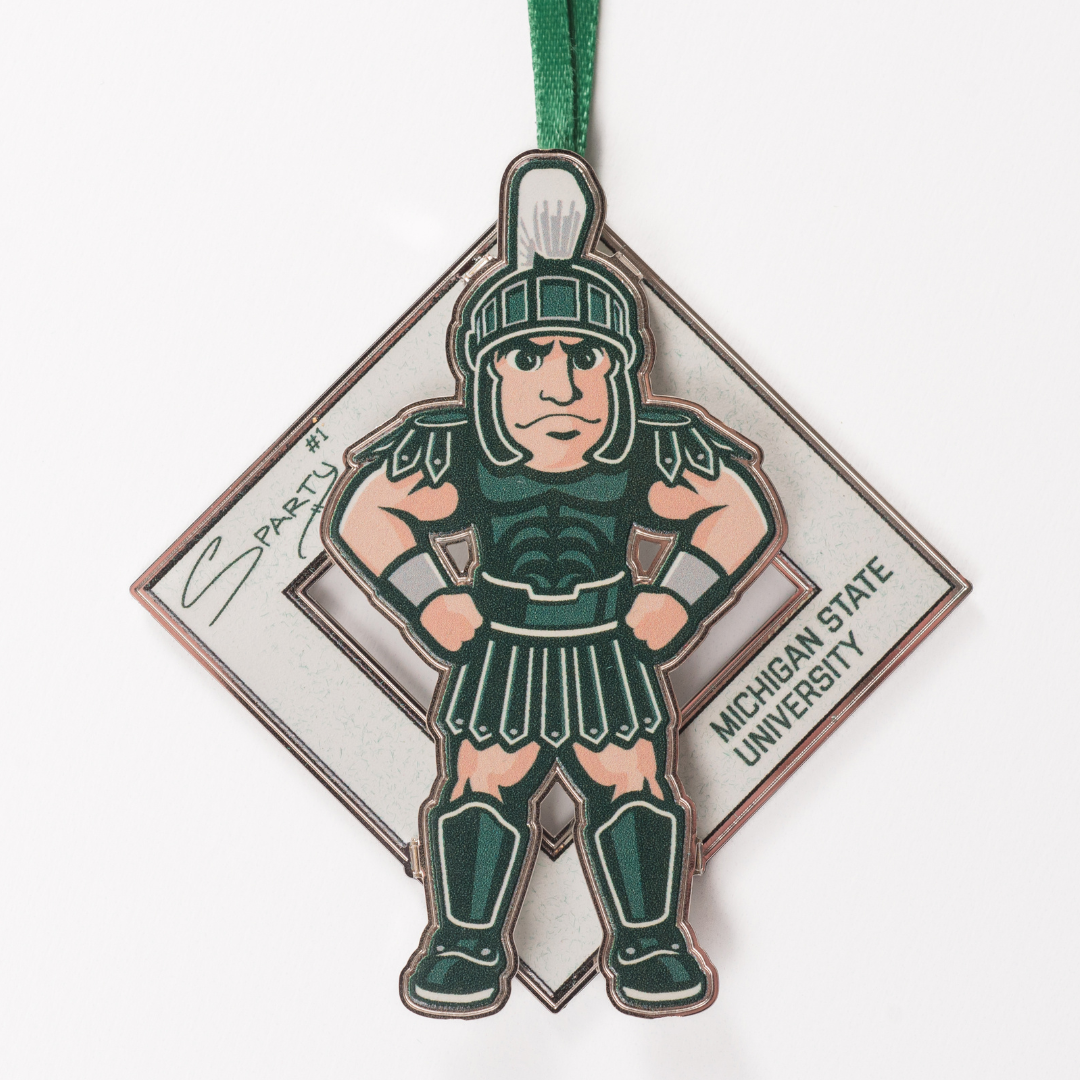 An illustration of MSU’s Sparty mascot sporting a smirk with his hands on his hips. A white diamond behind Sparty displays his "Sparty number 1" signature and athletic block letters that read Michigan State University. A green ribbon is affixed to the top of the collectible.