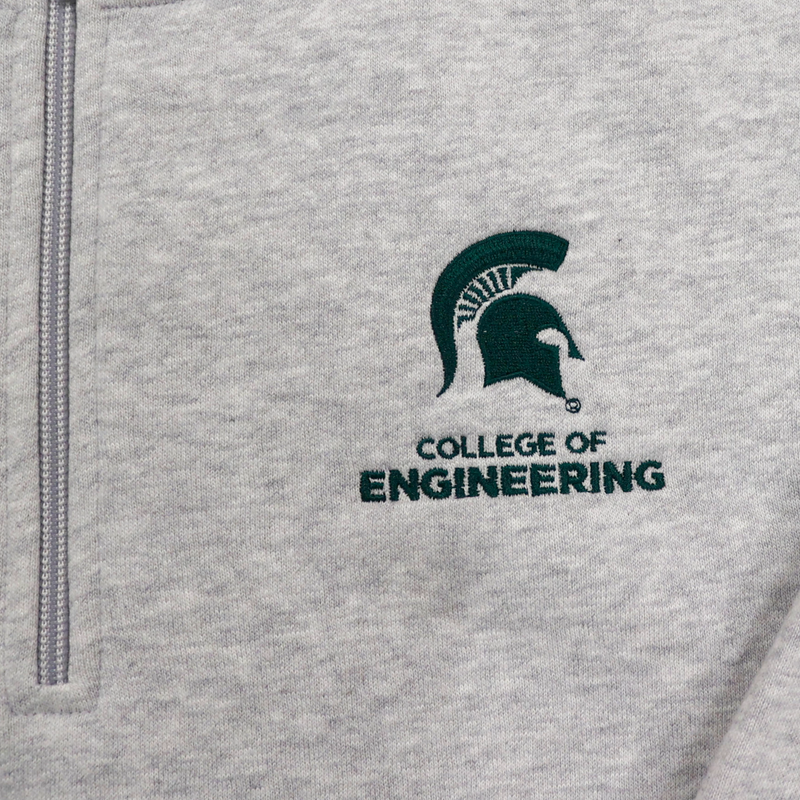 Close up of the chest logo of a heather gray quarter zip sweatshirt. The logo is a green MSU spartan helmet logo with "College of Engineering" written underneath.
