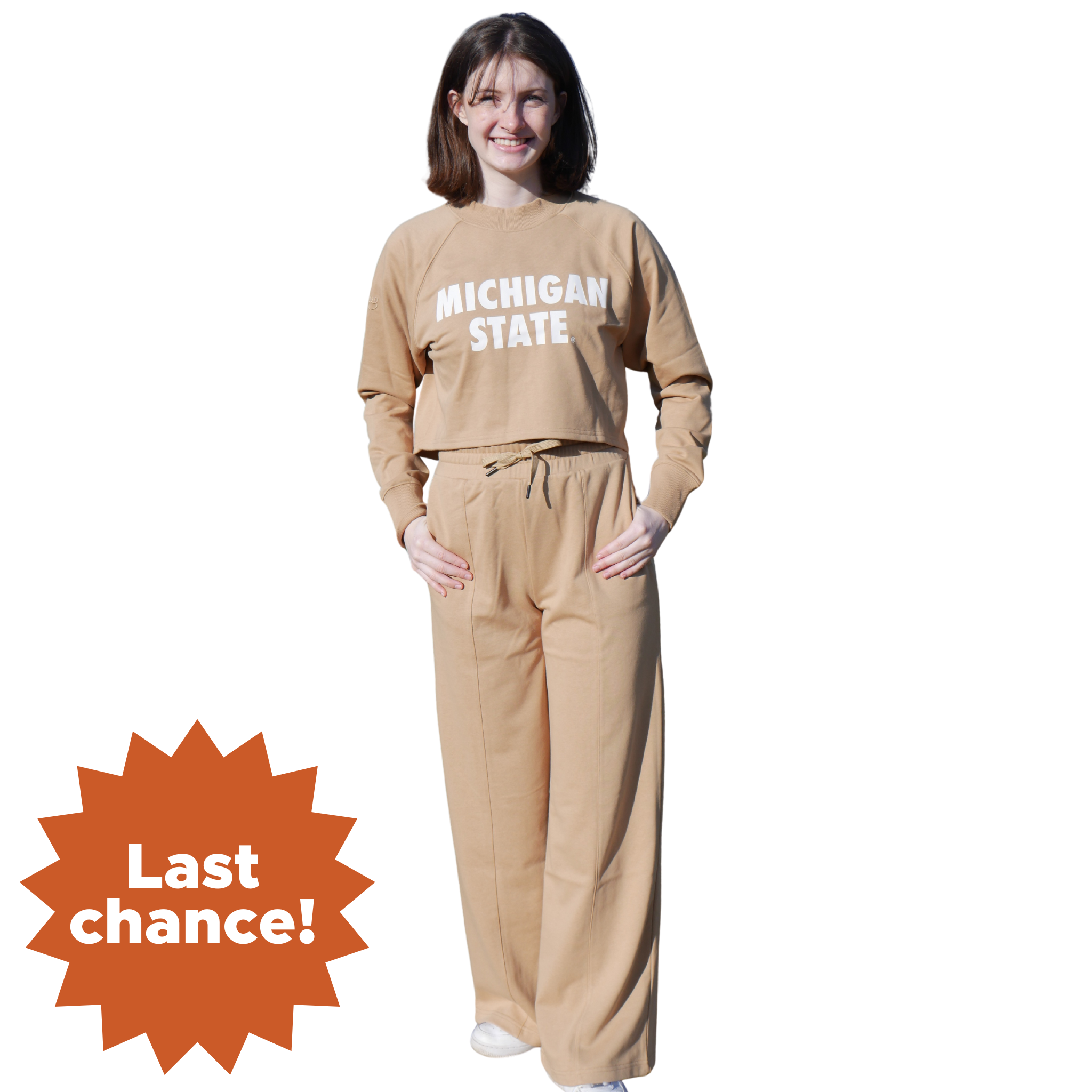 A woman wearing a tan cropped crewneck sweatshirt with matching sweatpants. On the sweatshirt reads "Michigan State" in white. In the lower left corner is an orange sunburst with the words "Last chance!"
