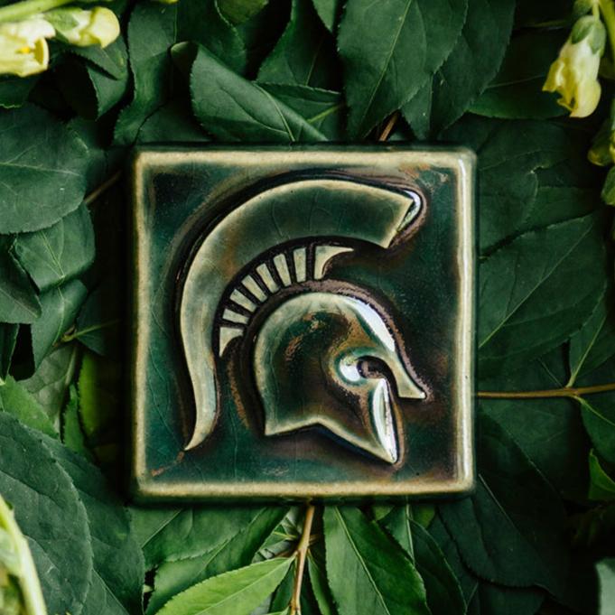 4" by 4" ceramic tile in green with raised MSU helmet in center. 