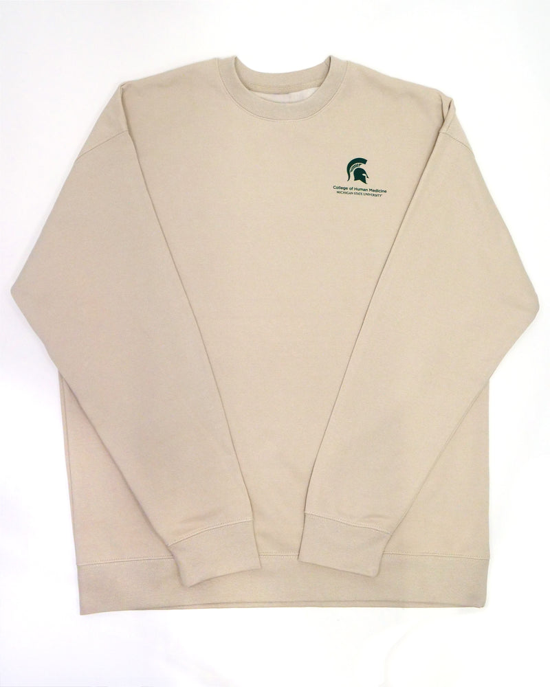 The front of a cream crewneck sweatshirt. In the top right corner is a green Michigan State spartan helmet logo with the words" College of Human Medicine, Michigan State University" written in green underneath. 