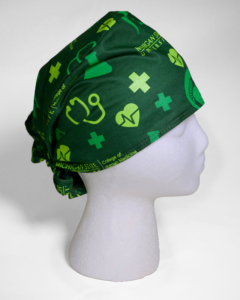 Forest green scrub cap on foam display head. Features lime green and kelly green medical icons all over print. Back tie. 