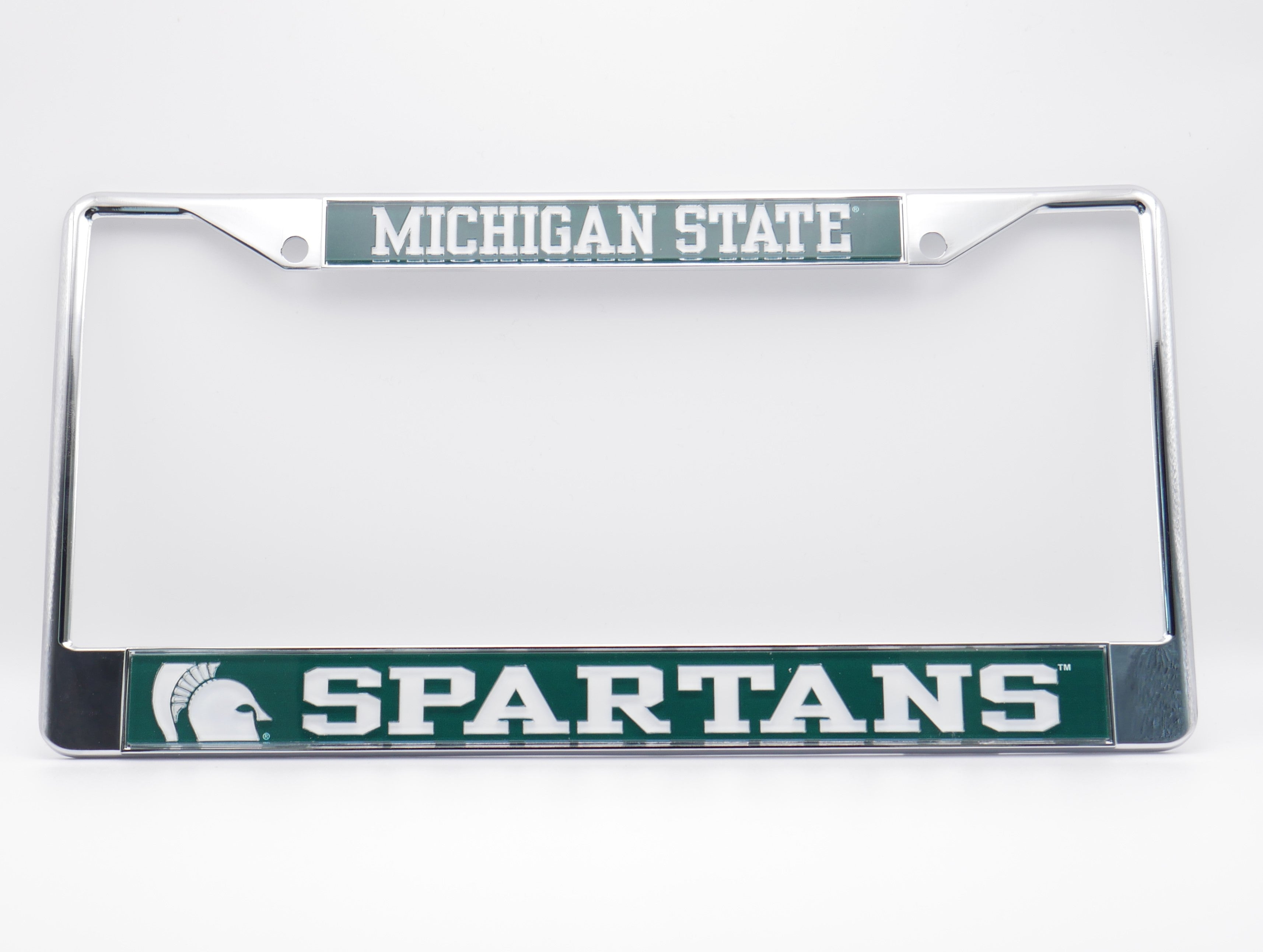 Chrome license plate frame with green colored bars along the top and bottom. Bar at the top is printed with Michigan State in white. Bar at the bottom is printed with a zoomed-in Spartan helmet and Spartans in white. The bars have mounting holes at each end.