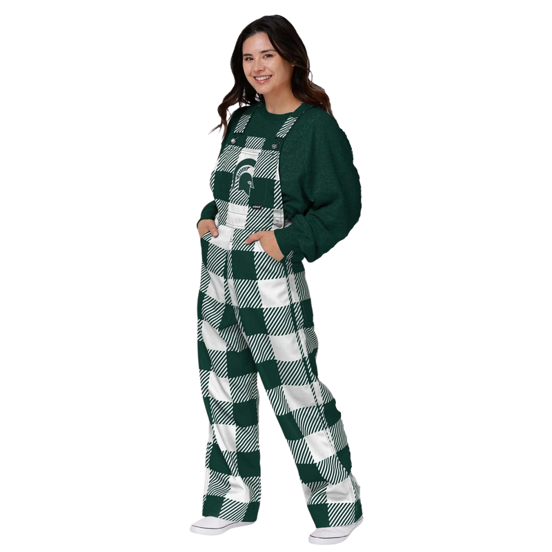 A woman wearing plaid Michigan State overalls. The colors alternate between green and white. In the center torso is a green MSU helmet logo.