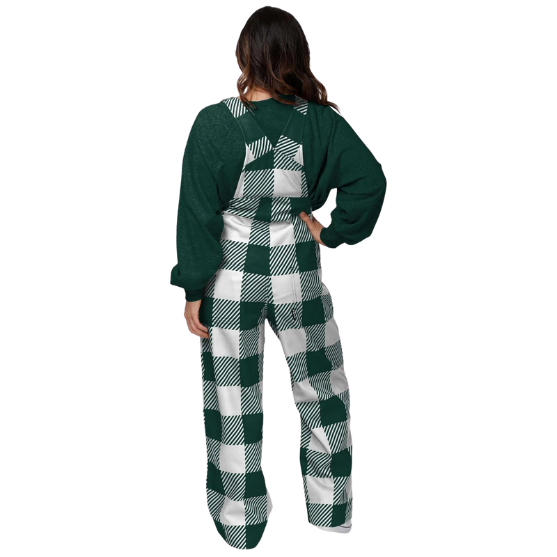 The back of a woman wearing plaid Michigan State overalls. The colors alternate between green and white. In the center torso is a green MSU helmet logo.