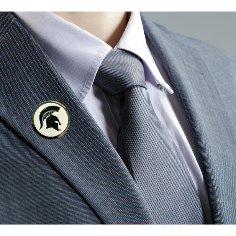 A close up of a suit with a chrome lapel pin that's white in the center and has a green Spartan helmet in the middle.