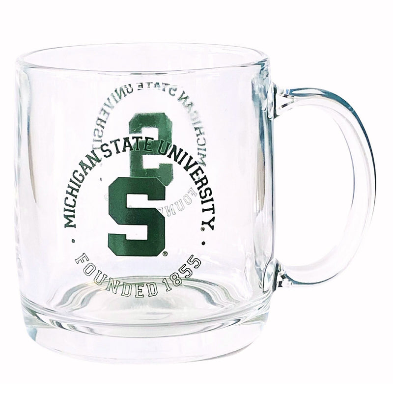 A clear glass mug with a curved handle and a solid glass base. On both sides is printed the Block S in dark green, encircled in the words "Michigan State University" in solid green on top and "Founded 1855" in outlined green beneath.