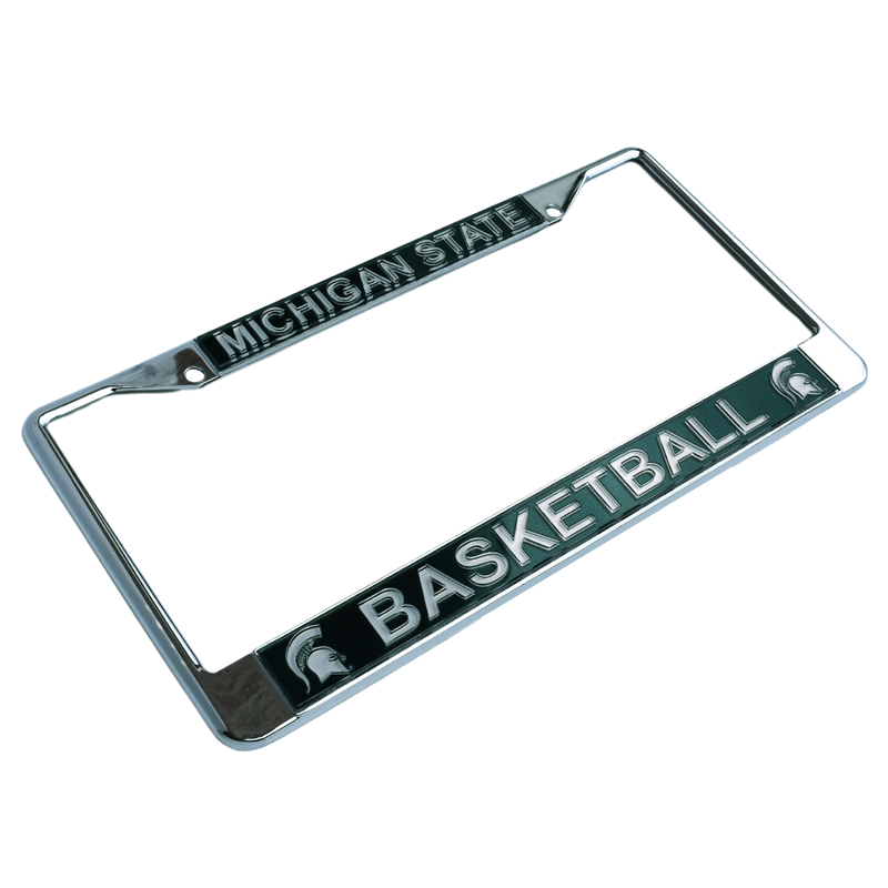 Three-quarters view of a chrome license plate with two screw holes at the top. A forest green block along the top reads "Michigan State" in all caps, and a matching block at the bottom reads "Basketball" between two Spartan helmets.