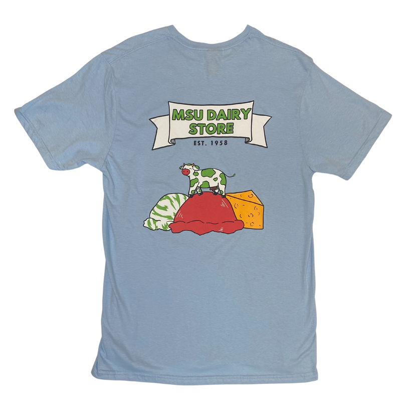 Back of a blue t-shirt with a large graphic on the back. Inside a white banner it reads MSU Dairy Store in green, and Est 1958 underneath. Below that is a cow with green spots standing on a red scoop of ice cream. To the left is a green and white scoop of ice cream and to the right is a wedge of orange cheese.