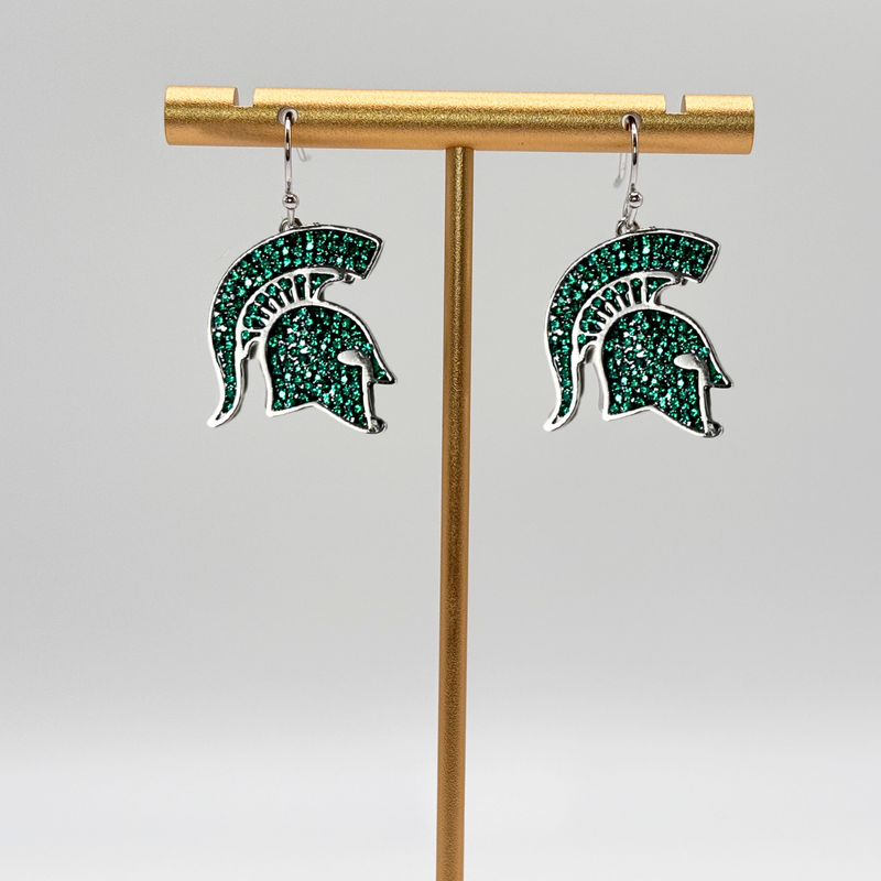 A pair of dangle earrings shaped as the Michigan State Spartan helmet logo. The logo is comprised of small green crystals with a rhodium plated brass outline.