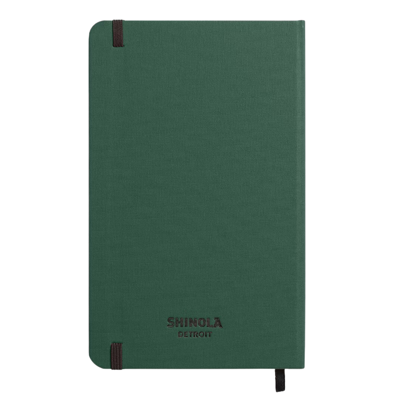 The back of a forest green linen journal with a black elastic enclosure band, and Shinola Detroit embossed on the bottom.