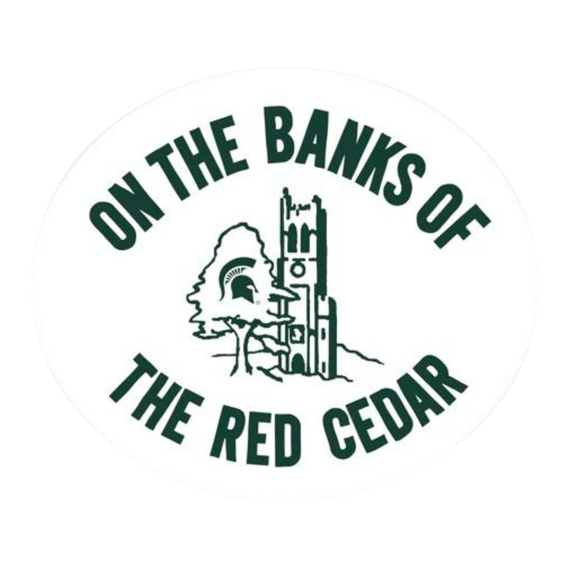 White circular sticker with Beaumont Tower and a tree with a Spartan helmet logo on it with the writing "On The Banks Of" above the center and "The Red Cedar" below.