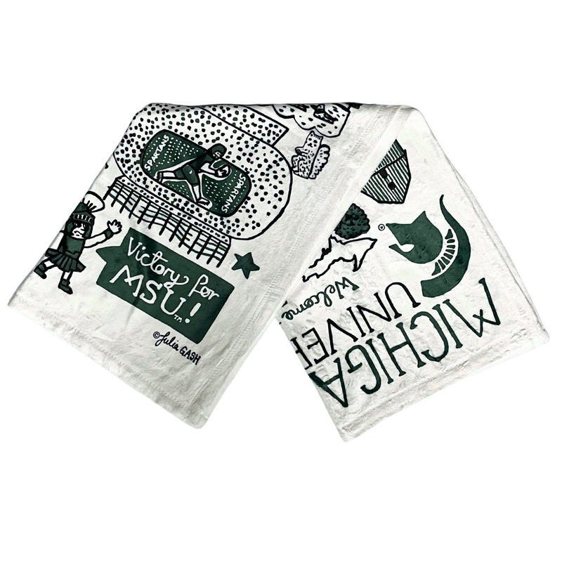 A folded white, plush fleece blanket measuring 30 inches wide and 40 inches high. On the blanket are multiple drawings of various Michigan State University landmarks.