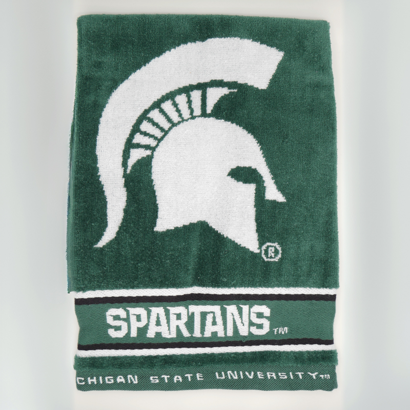 The front portion of a dark green golf towel with a large white Michigan State spartan helmet logo in the center. Underneath the helmet logo is the word "Spartans" written in the MSU athletics font. Underneath Spartans, in smaller font, are the words Michigan State University. 