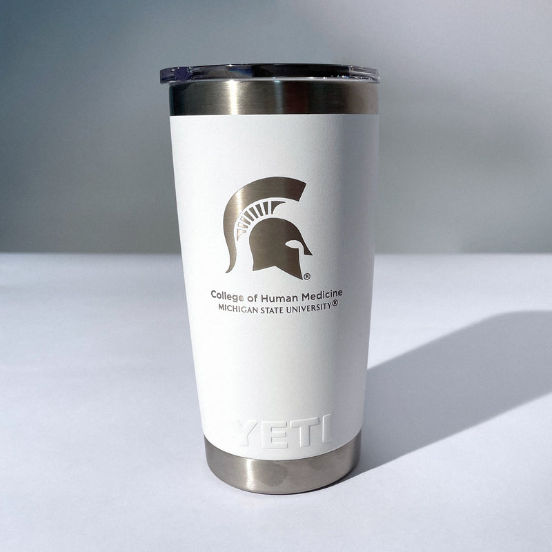 A white, 20-ounce beverage tumbler with a silver etched logo that includes a picture of the spartan helmet and the words Michigan State University College of Human Medicine.