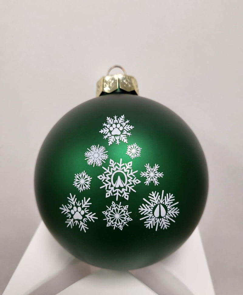 Green ball ornament with gold tone top. Snowflake pattern with pay prints in the centers printed in white on center. 