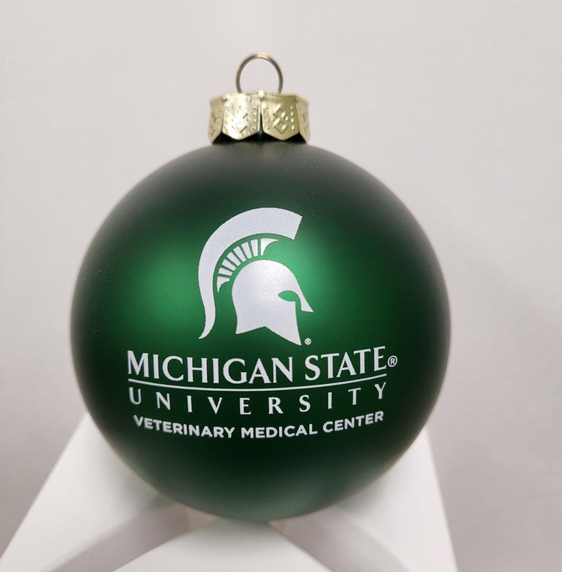 Green ball ornament with gold tone top. Spartan helmet and Michigan State University Veterinary Medical Center printed in white in center. 