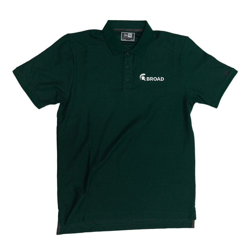 Dark green polo shirt with three green buttons from the collar. On the left chest is white embroidery of a spartan helmet and Broad in all caps