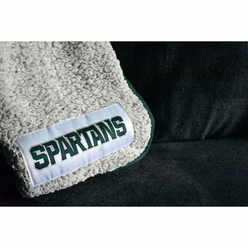 Close-up of the Spartans applique in the bottom corner of the blank, which is folded and laying on a charcoal couch