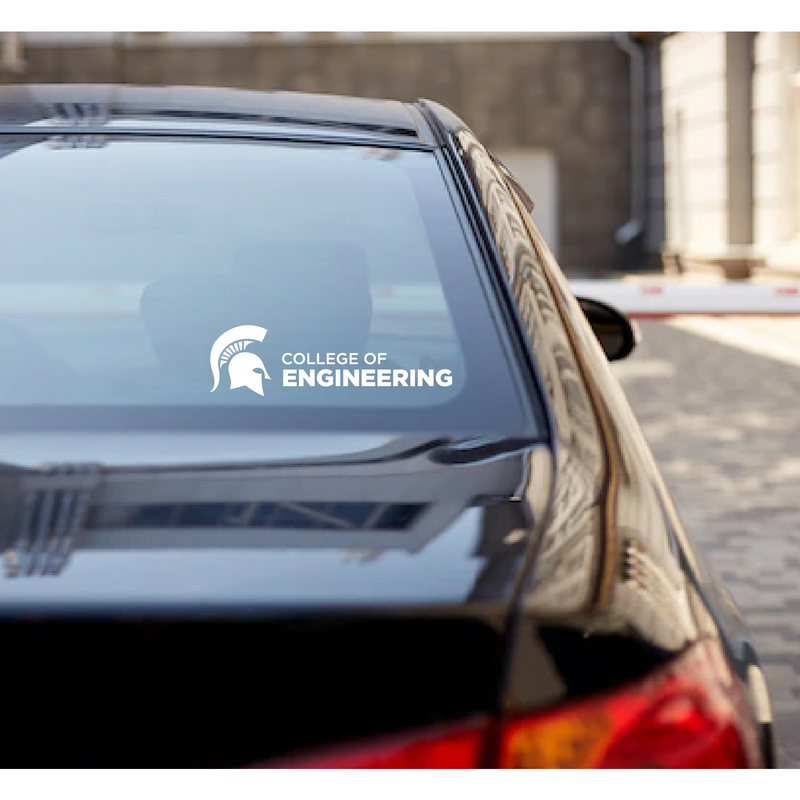 Decal reading College of Engineering Alumni in all caps next to a white Spartan helmet on the back rear windshield of a dark sedan.