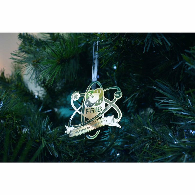Bottom up view of the FRIB 2022 Michigan State University ornament hanging in a decorated holiday tree.