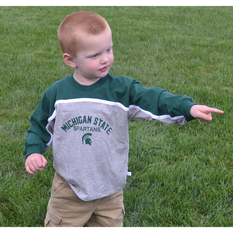 A child wearing a grey and green Michigan State Spartans long sleeve tee shirt. The sleeves of the shirt are green while the torso is grey.