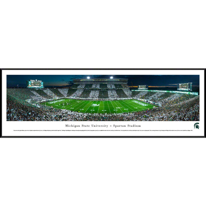 A framed panoramic view of a filled Spartan Stadium at night. The crowd in the stands of the stadium have groups alternating wearing green and white.