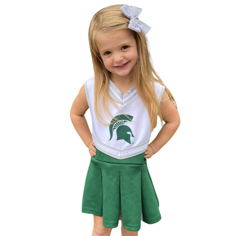 Little girl wearing the children's cheerleader outfit with her hands on her hips and white hair bow to match.