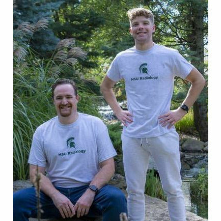 Two men stand in the gardens wearing the gray crewneck t-shirt