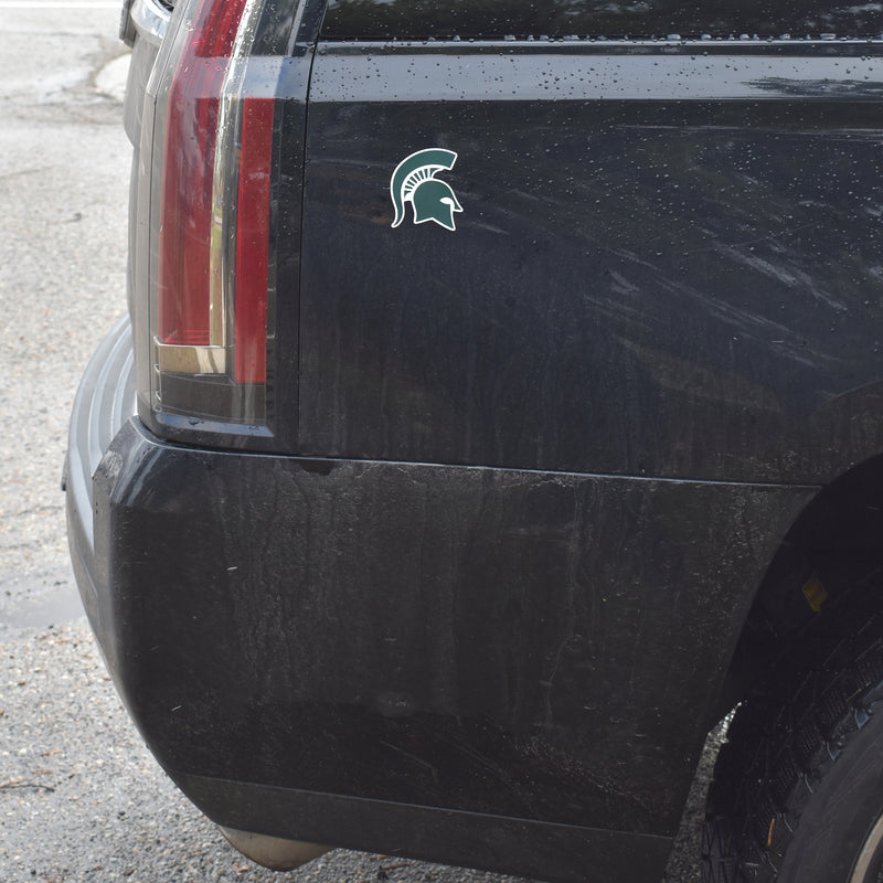 A magnetic Spartan helmet decal is affixed to the rear passenger side of a black SUV.