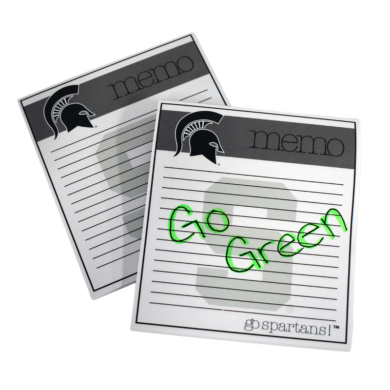 Square notepad with a tan block along the top reading "memo" with a dark Spartan helmet on the left. In the center of the pad are 14 lines, with a watermark block S. At the bottom, thin font reads "go Spartans!" On one of the memo pads is a handwritten note that reads go green