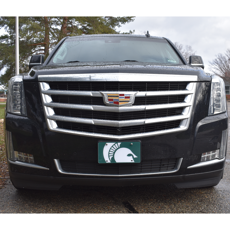 The Spartan Helmet Mega Logo license plate affixed to the front of a Black cadillac SUV