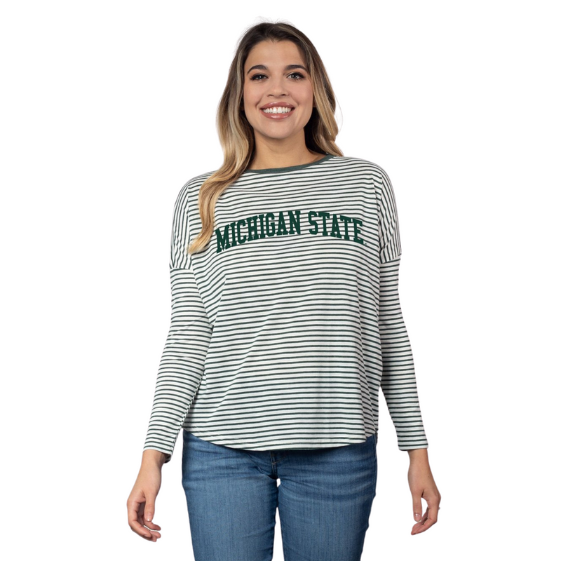 Woman wearing a long-sleeved crewneck t-shirt. The shirt is white with thin green horizontal stripes. The sleeve hem is halfway down the upper arm. Green printing in the center chest reads Michigan State