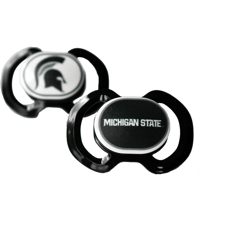Two black pacifiers each with a different center decorative piece. In the back, a white oval displays a black Spartan helmet. In the front, a black oval reads Michigan State in block white text.