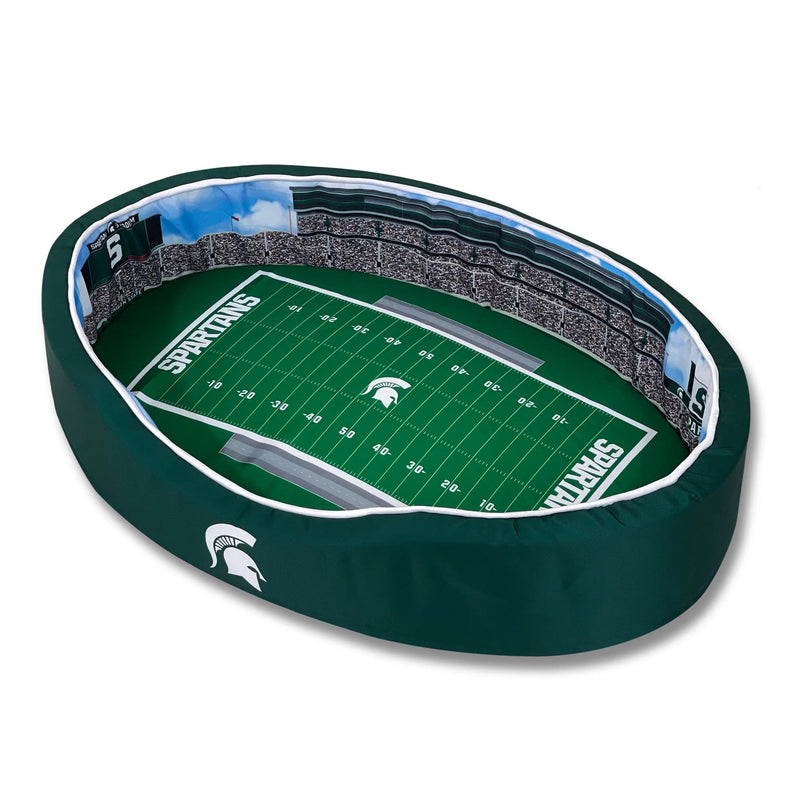 Oval dog bed printed on the inside to resemble Spartan stadium on game day with packed stands and a football field in the center.