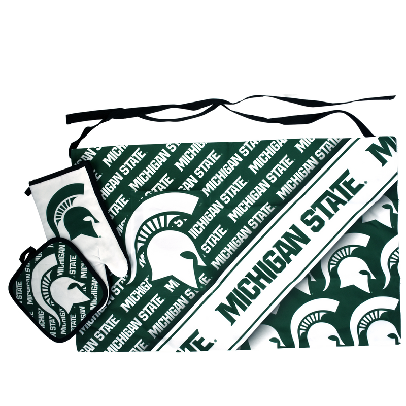 Green and white waist apron with various Michigan State graphics patterned across and a large pocket on the right thigh. A white oven mitt with a green Spartan helmet is layered on top, with a potholder patterned in green and white on top of that.