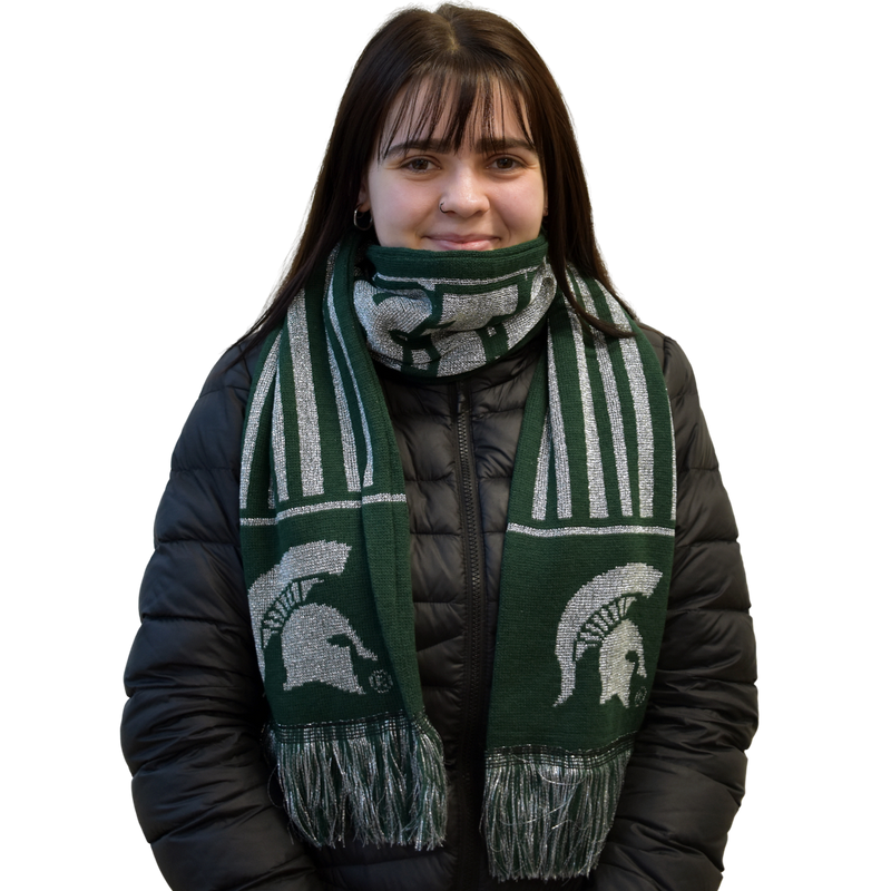 Front view of a woman in a black puffy coat with the dark green and silver striped scarf wrapped once around her neck. The silver Spartan helmet on either end of the scarf are proudly displayed over the fringed ends of the scarf.