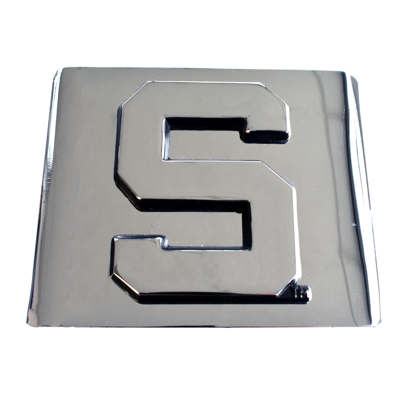 A 3D chrome Spartan block S is affixed to a chrome tow hitch cover, shown from a front view