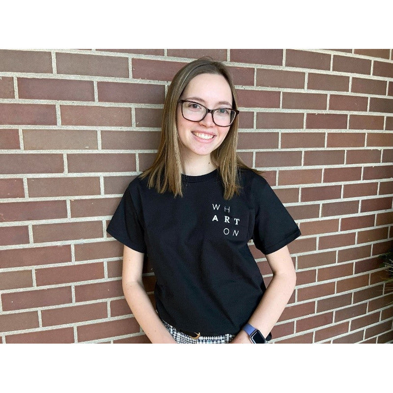 Female student wearing black Wharton Center t-shirt in front of a brick wall
